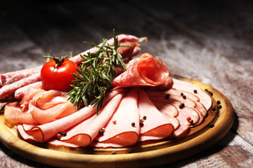 Food tray with delicious salami, pieces of sliced ham, sausage and salad. Meat platter selection.
