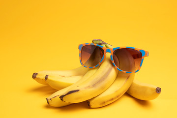 bananas and sunglasses on a yellow background © Serge Touch