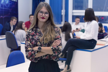 Students life on the campus.Portrait of female college student smiling and looking at camera during class in the classroom.