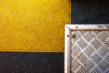 A silver steel plate that crosses a yellow plate on a graphite background. Intersecting plates form...