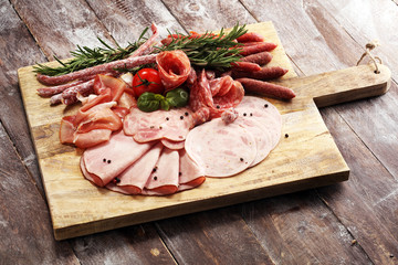 Food tray with delicious salami, pieces of sliced ham, sausage and salad. Meat platter selection.