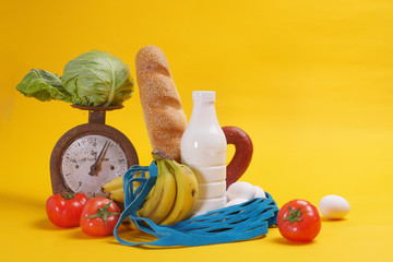 products, fruits, vegetables on scales and in a shopping bag on a yellow background