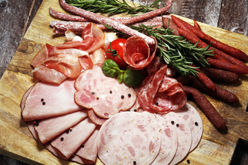 Food tray with delicious salami, pieces of sliced ham, sausage and salad. Meat platter selection.