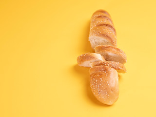 Baguette with sesame seeds, cut into slices on a yellow background