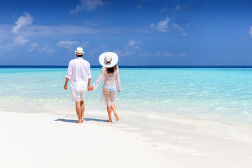 Verliebtes Paar läuft Hand in Hand am tropischen Strand der Malediven und genießt seine...