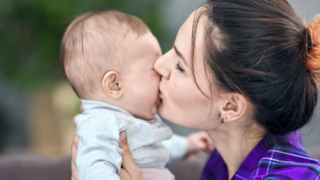 Close-up caring young mother kissing and calm down crying little cute child