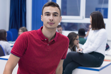 Students life on the campus.Portrait of male college student smiling and looking at camera during class in the classroom. University male american student standing  in classroom.