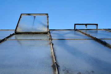 Garden shed closeup on a sunny day. You see the open windows for air flow and a clear sky.