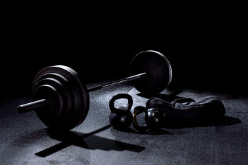 BACK LIT image of 365 pound weight on barbell with kettle bells and sand bag on gym floor - 264284883