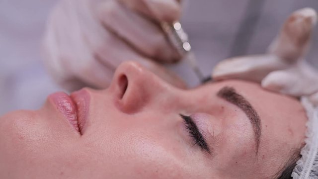 Side, close-up, of a girl who is on the procedure of permanent makeup. 4K Slow Mo
