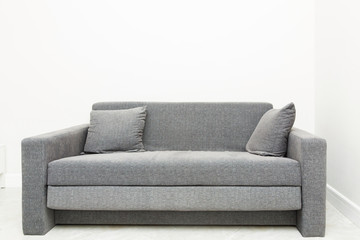 Classic modern gray sofa with pillows in the bright interior of the apartment