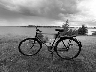 Obraz premium Adult road bike on the bank of a cloudy river.