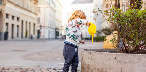 Kind gießt auf städtischem Platz Pflanzen. Kid watering urban garden plants on city square. © Lukas Bast