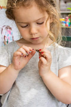 A toddler aged girl looking at a bug outside on a porch.