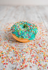Obraz na płótnie Canvas donut with colorful sprinkles on white wooden background