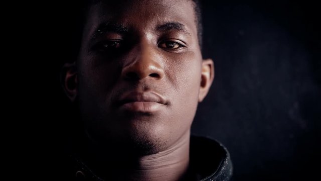 Confident angry black african man staring at camera in the dark