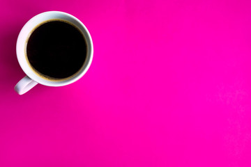 Obraz na płótnie Canvas One cup of coffee on a bright pink background. A cup with a coffee photographed from the top and with a place for copy space. Morning coffee