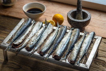 Raw saury on a grill for smoking with lemon and herbs top view