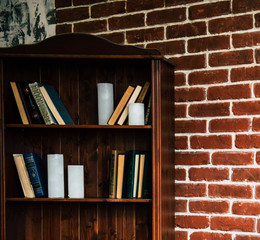 Decor in the style of loft, with a brick wall, a cabinet with books and a lamp