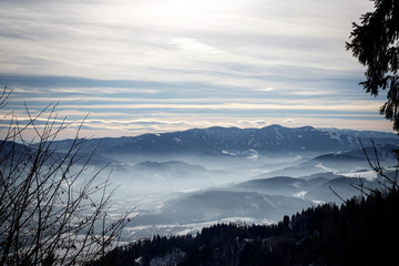 alpine winter panorama with a misty valley and mountains foggy winter sky in the european alps