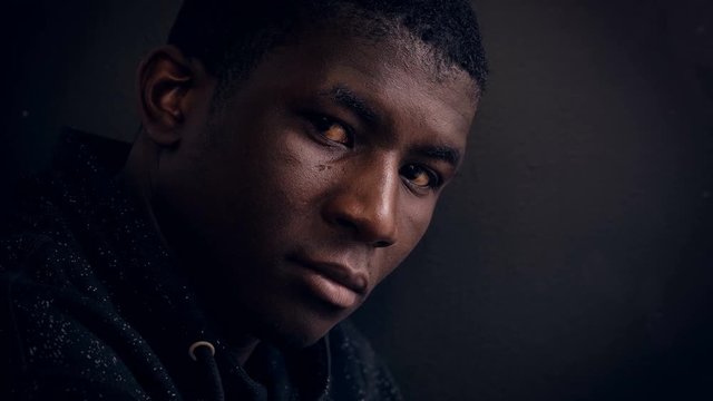 Confident serious young black african man in the dark,staring at camera