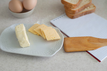 We cook breakfast. In the photo: flour, eggs, bread, cheese, notebook, olive oil, butter and wheat sprouts