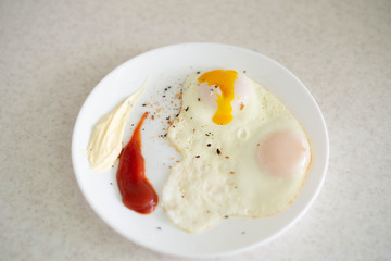 Breakfast in the form of egg with sauces on a white plate