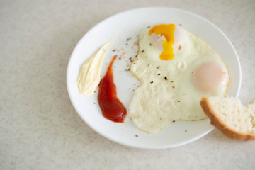 Breakfast in the form of egg with sauces on a white plate