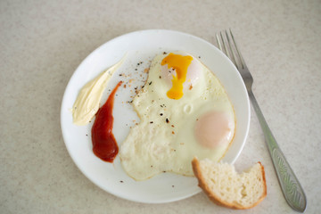 Breakfast in the form of egg with sauces on a white plate