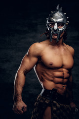 Strong shirtless gladiator in helmet is showing his muscules. He is wearing bandage.