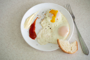 Breakfast in the form of egg with sauces on a white plate