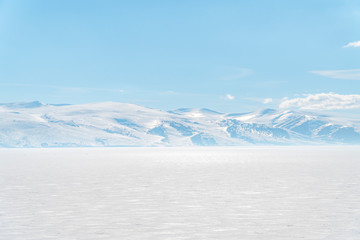 frozen lake with surrounding snow covered rocky mountains 