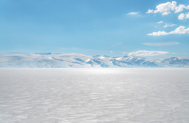 Fototapeta na wymiar frozen lake with surrounding snow covered rocky mountains 