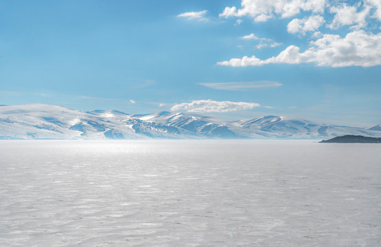 frozen lake with surrounding snow covered rocky mountains 