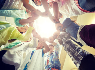 education, school, teamwork and people concept - international students making circle of hands