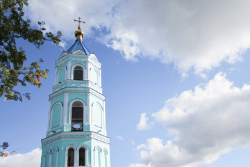 The bell tower of the Christian Church on a Sunny summer day against a blue sky with clouds.
