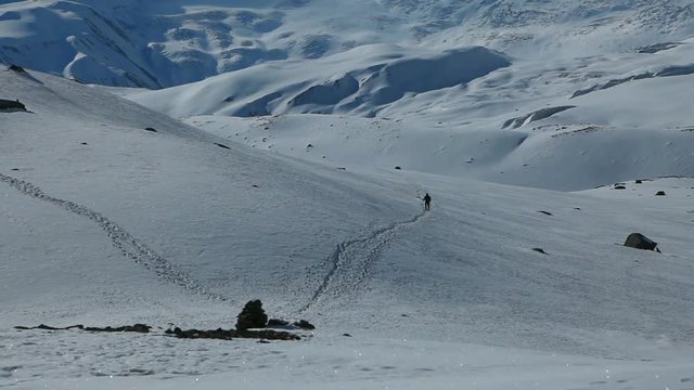 Group of hikers in the snowy mountains. Panoramic shot of Tilicho lake area and high snowy and icy mountains around. Hiking and trekking in Nepal, spring trek around Annapurna mount.