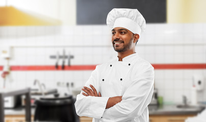 cooking, profession and people concept - happy male indian chef in toque over restaurant kitchen background