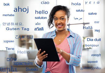 technology, translation and people concept - happy african american woman using tablet computer...