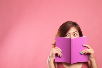 Young Asian woman with a book cover her face.