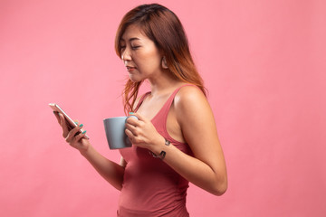 Naklejka premium Young Asian woman with mobile phone and coffee cup.