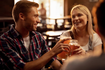 Happy couple toasting with beer in a pub.