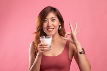 Healthy Asian woman drinking a glass of milk show OK sign.