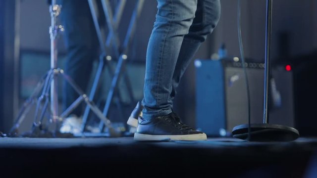 Soloist on stage, rock music. Musician stomps foot during concert
