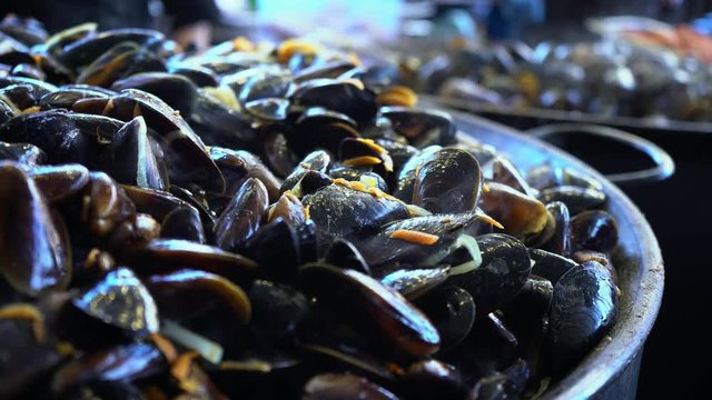Mussels in the shell. Cook fries mussels in a large frying pan. Seafood. Seafood delicacies. Clams. Fish restaurant. Vitamins, minerals and trace elements. Iron, manganese, phosphorus, potassium, zinc