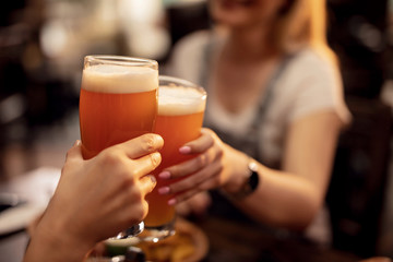 Close up of a couple toasting with beer in a pub.