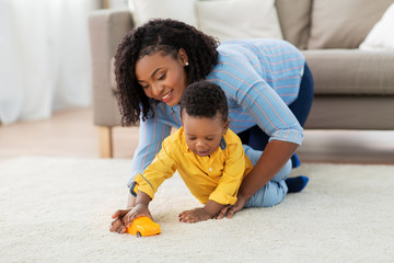 childhood, kids and people concept - happy african american mother and her baby son playing with...