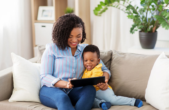 family, motherhood and technology concept - happy african american mother using tablet computer with little baby son at home