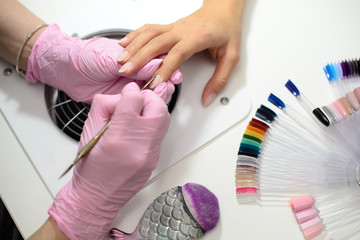 Closeup shot of a woman in a nail salon receiving a manicure by a beautician with nail file. Woman getting nail manicure. Beautician file nails to a customer.