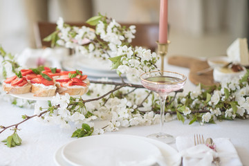 Laying and decor of the wedding banquet table. Plates, knives, forks, glasses, plates, flowers, snacks and fruit. The main thing in the details.